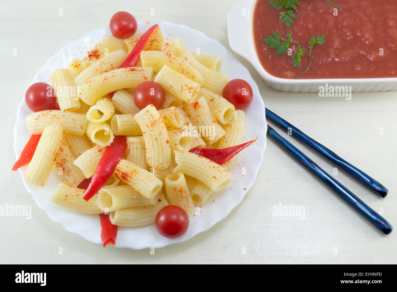 Pasta con pomodori ciliegia e pepe rosso servito con una salsa di pomodoro in un bianco prua per mangiare con le bacchette in Asia Foto Stock