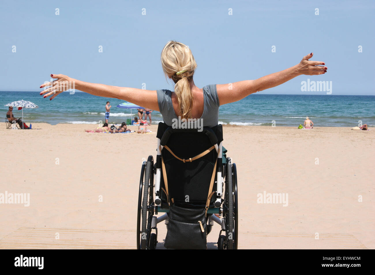 Donna che utilizza una sedia a rotelle su una spiaggia Foto Stock