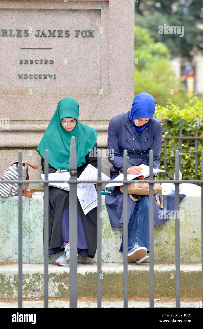 Londra, Inghilterra, Regno Unito. Giovani femmine studenti musulmani per lavorare in esterno dalla statua di Charles James Fox in Bloomsbury Square Foto Stock