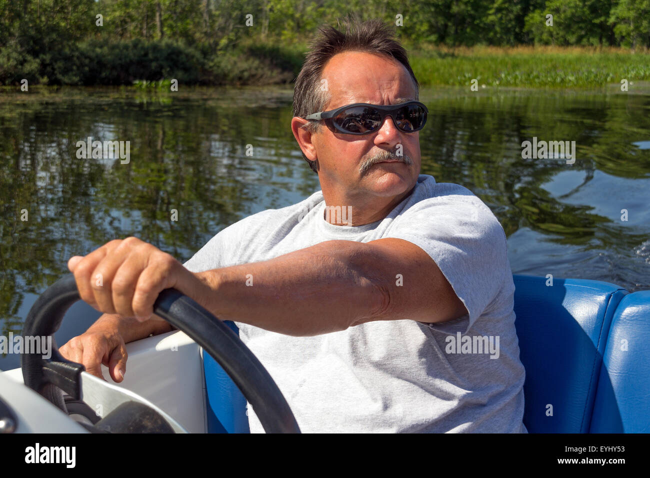 Gli uomini di età matura la guida con una barca a motore in un fiume Foto Stock