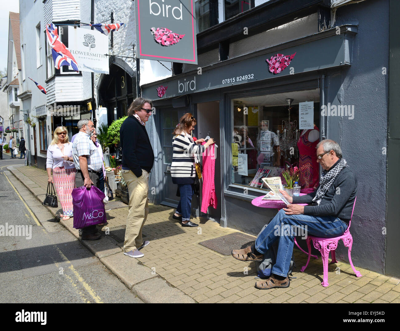 Uomo seduto in rosa uomo sedia a signori vestiti fashion shop store in Dartmouth Regno Unito Foto Stock