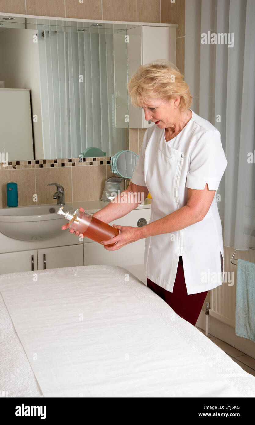 Massaggiatrice la preparazione di olio per il suo cliente nella sala di trattamento Foto Stock