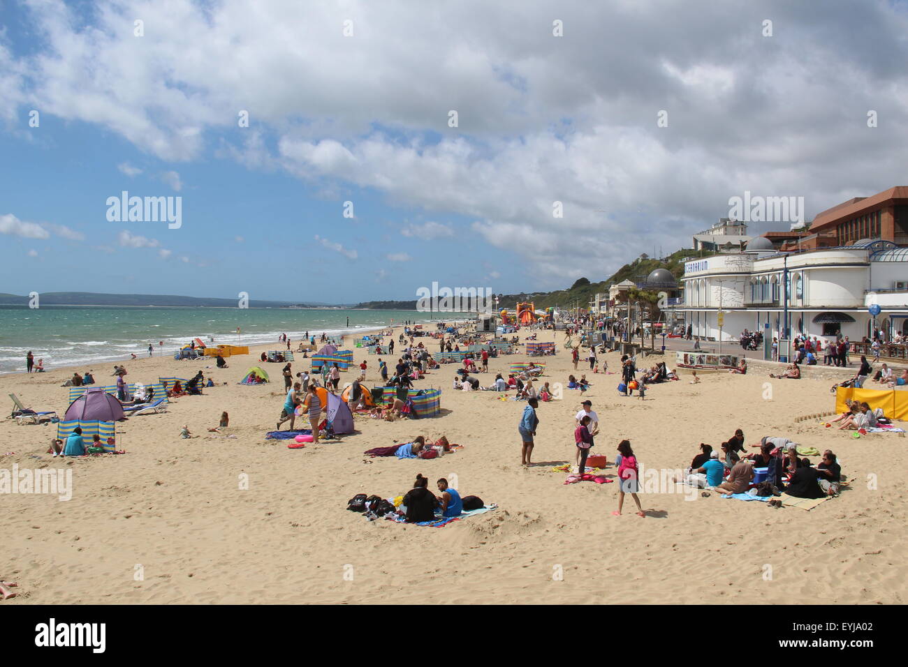 Una soleggiata vista della spiaggia di Bournemouth nel Dorset in un giorno di estate con alcuni FAIRWEATHER CLOUD e molte persone sulla spiaggia sabbiosa Foto Stock