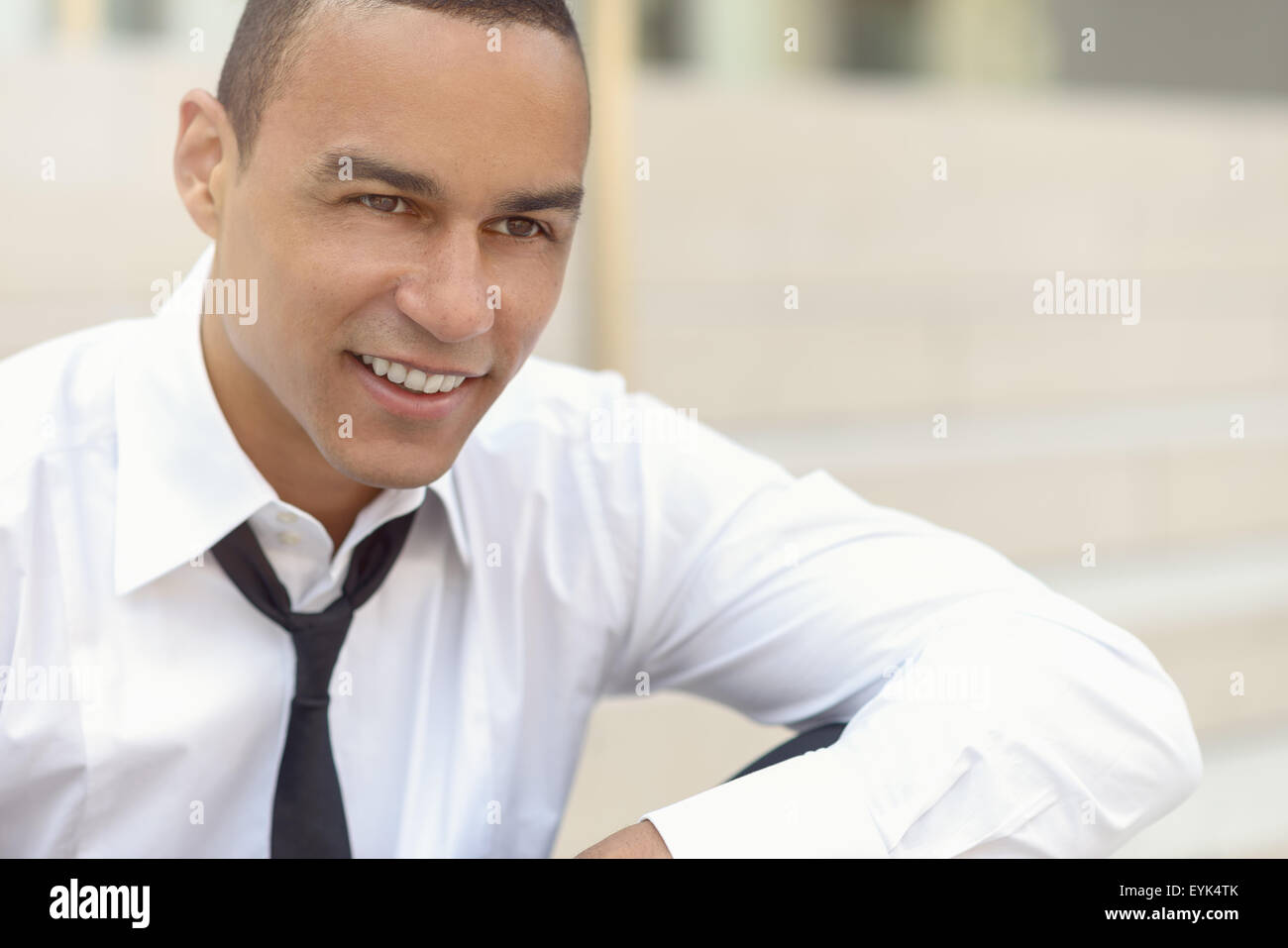 Attraente imprenditore sorridente con una fascetta allentata e il suo collare rimosse guardando al lato destro del telaio, closeup hea Foto Stock