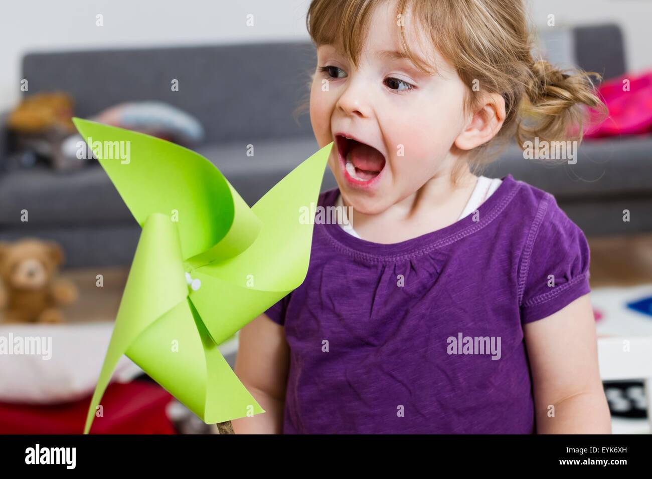 Ragazza eccitato oltre il mulino a vento di carta a casa Foto Stock