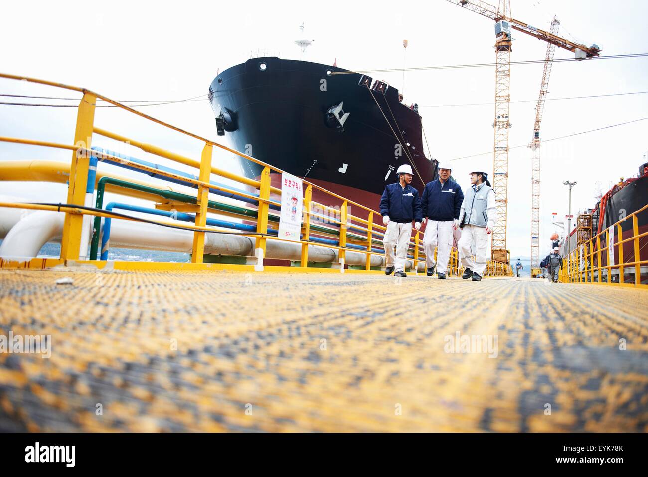 Tre lavoratori al porto di spedizione, basso angolo visuale, GoSeong-gun, Corea del Sud Foto Stock