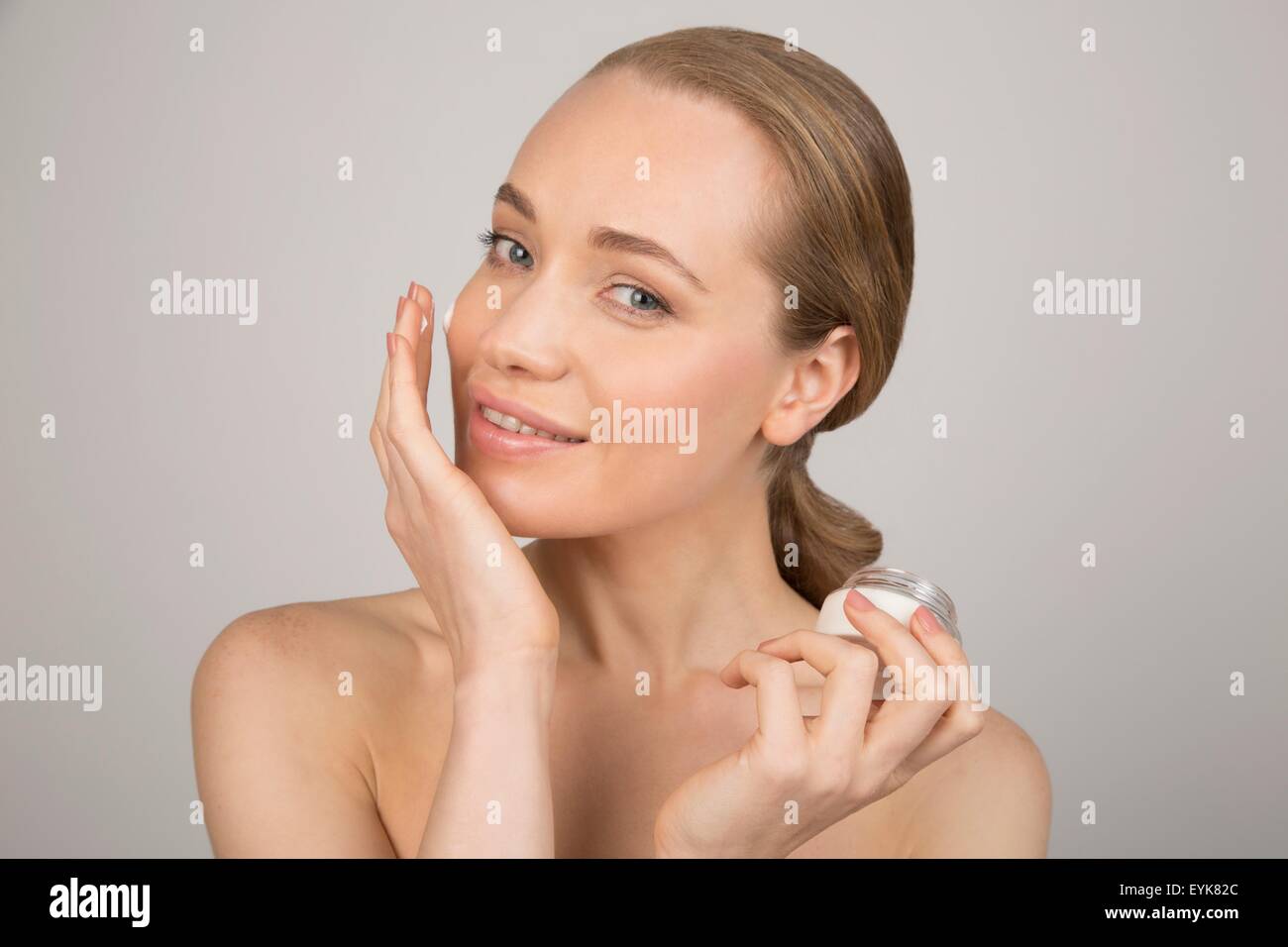 Profilo della giovane donna l'applicazione di crema di bellezza al viso Foto Stock