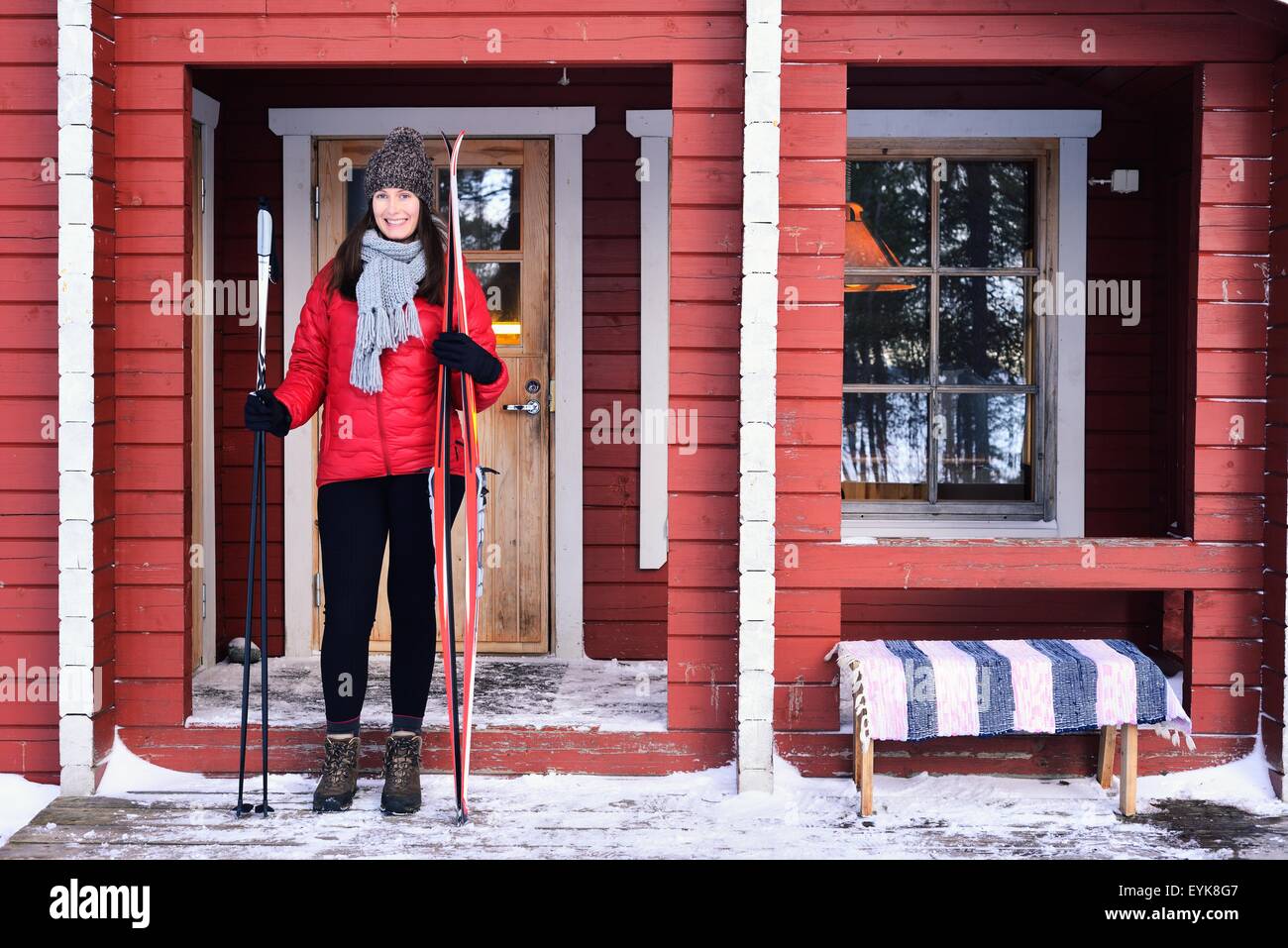 Ritratto di giovane donna sciatore sul portico di cabina, Posio, Lapponia, Finlandia Foto Stock