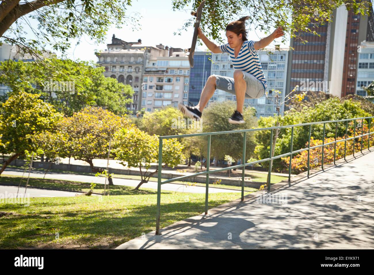 Giovane uomo facendo saltare sullo skateboard sulle ringhiere Foto Stock