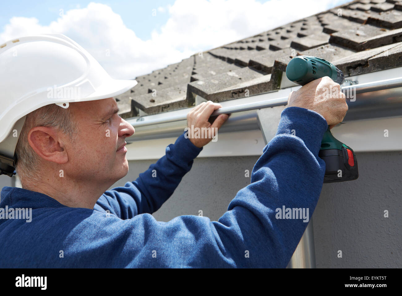 Workman sostituzione grondaie sull esterno della casa Foto Stock