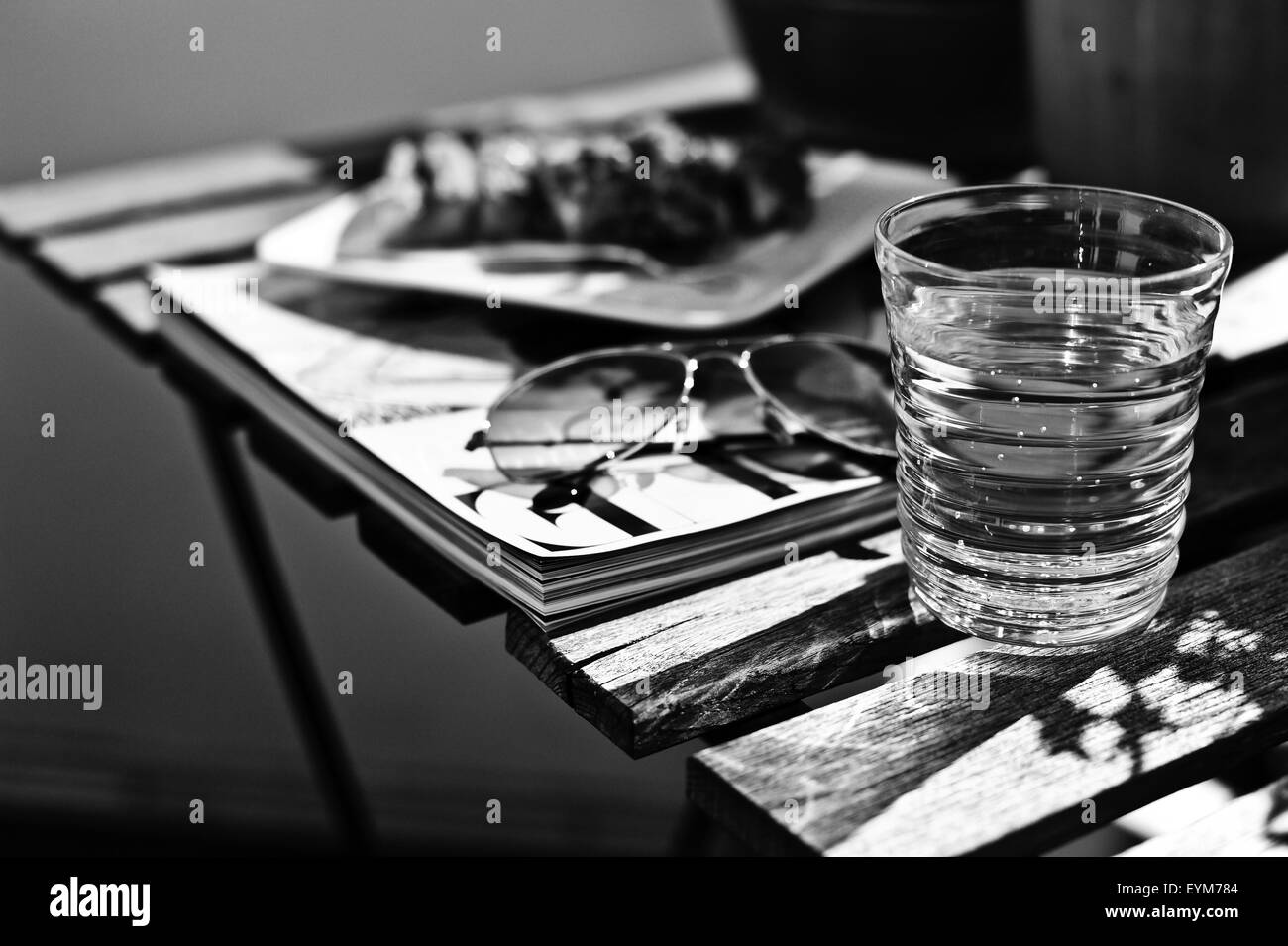 Bicchiere di acqua nella luce del sole su un tavolo di legno, Foto Stock