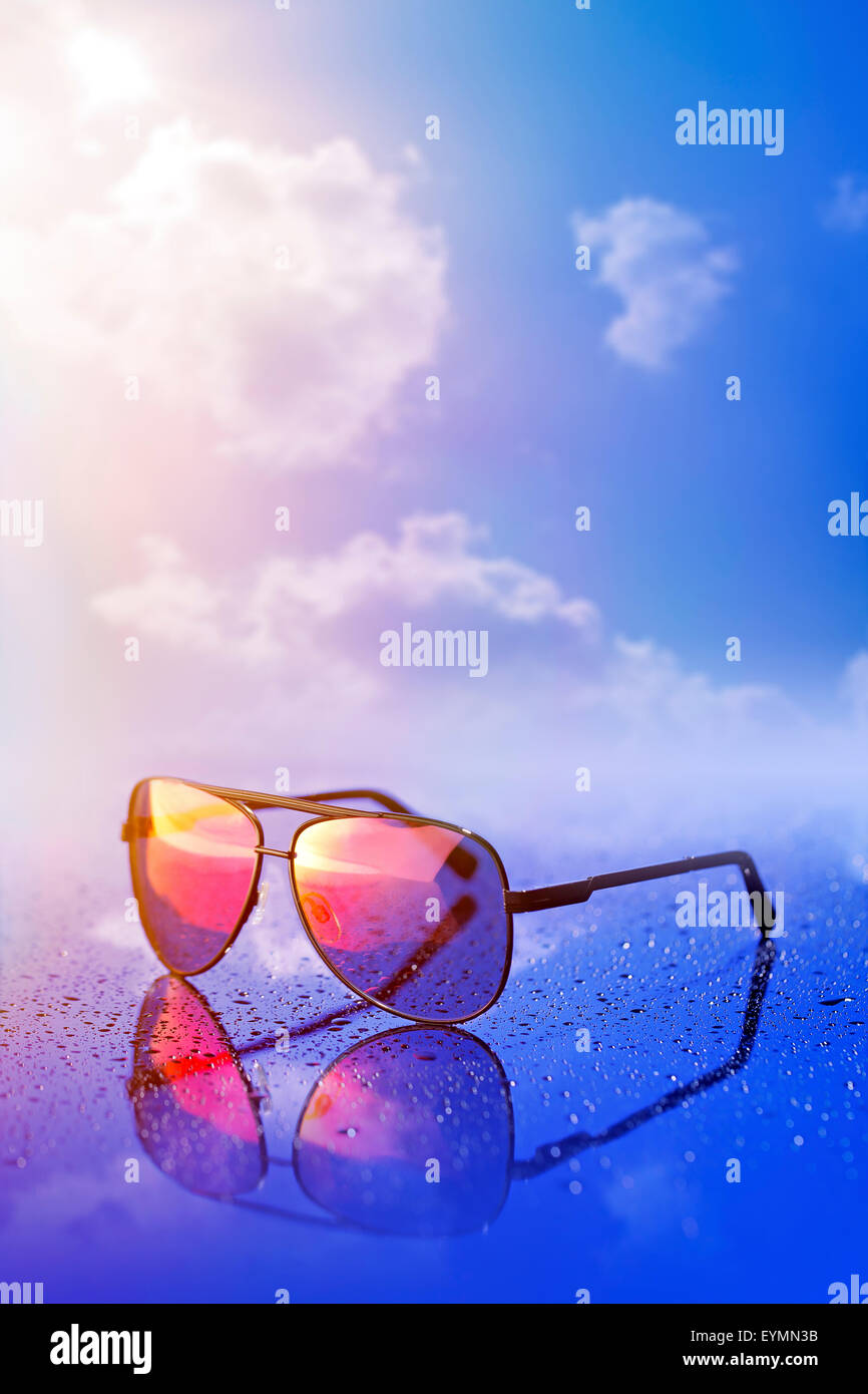 Nuovi occhiali da sole sul bagnato la superficie riflettente. Foto Stock