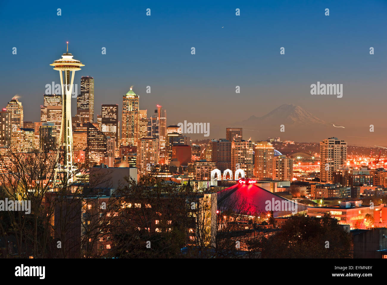 Lo skyline di Seatlle dopo il tramonto al crepuscolo in un freddo inizio inverno sera con bella neve coverred Mount Rainier in backgr Foto Stock