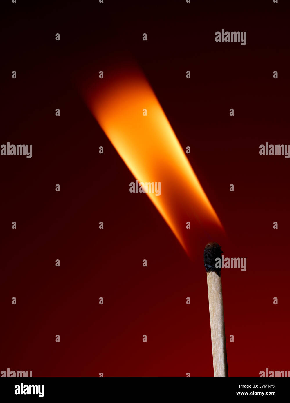 Ripresa macro di una fiammante matchstick su uno sfondo rosso Foto Stock