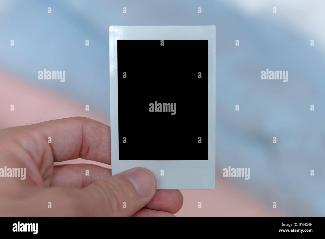 Una mano d'uomo in possesso di una pellicola istantanea print riempita con un solido spazio nero per personalizzare con la propria immagine. Foto Stock