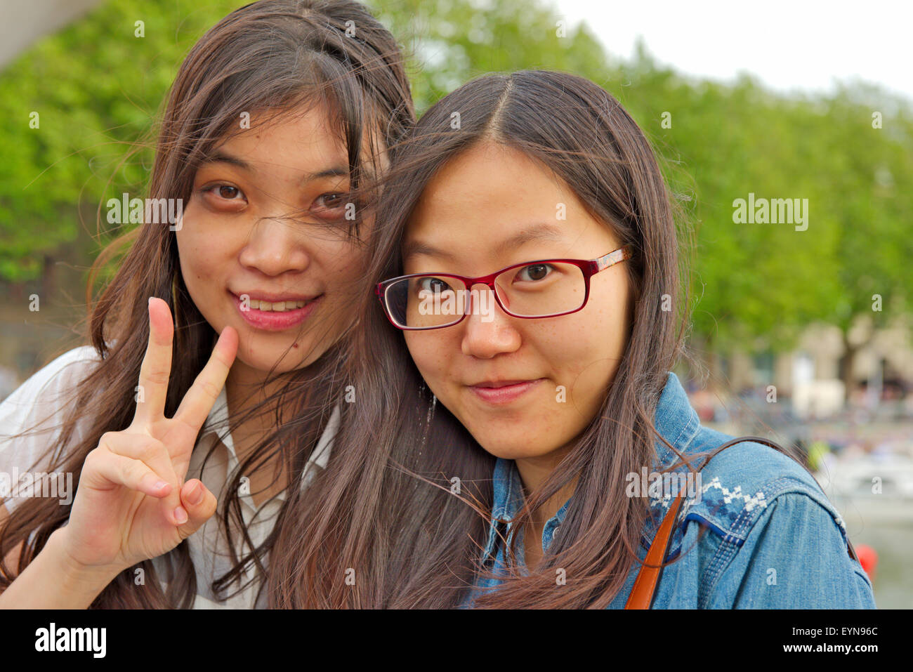 Ritratto di due giovani attraenti donne asiatiche, uno dando "V" segno Foto Stock