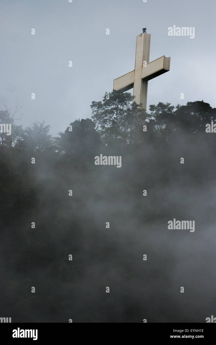 Un'alta croce cristiana è vista attraverso la nebbia su un crinale a Bukit Kasih, una popolare destinazione turistica religiosa a Minahasa, Sulawesi Nord, Indonesia. Foto Stock