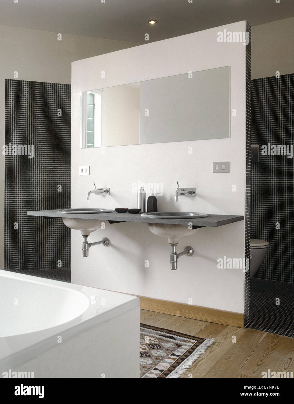 Vista interna di una moderna stanza da bagno in primo piano il bacino di vanità e lo specchio che si affaccia su sanitary ware Foto Stock