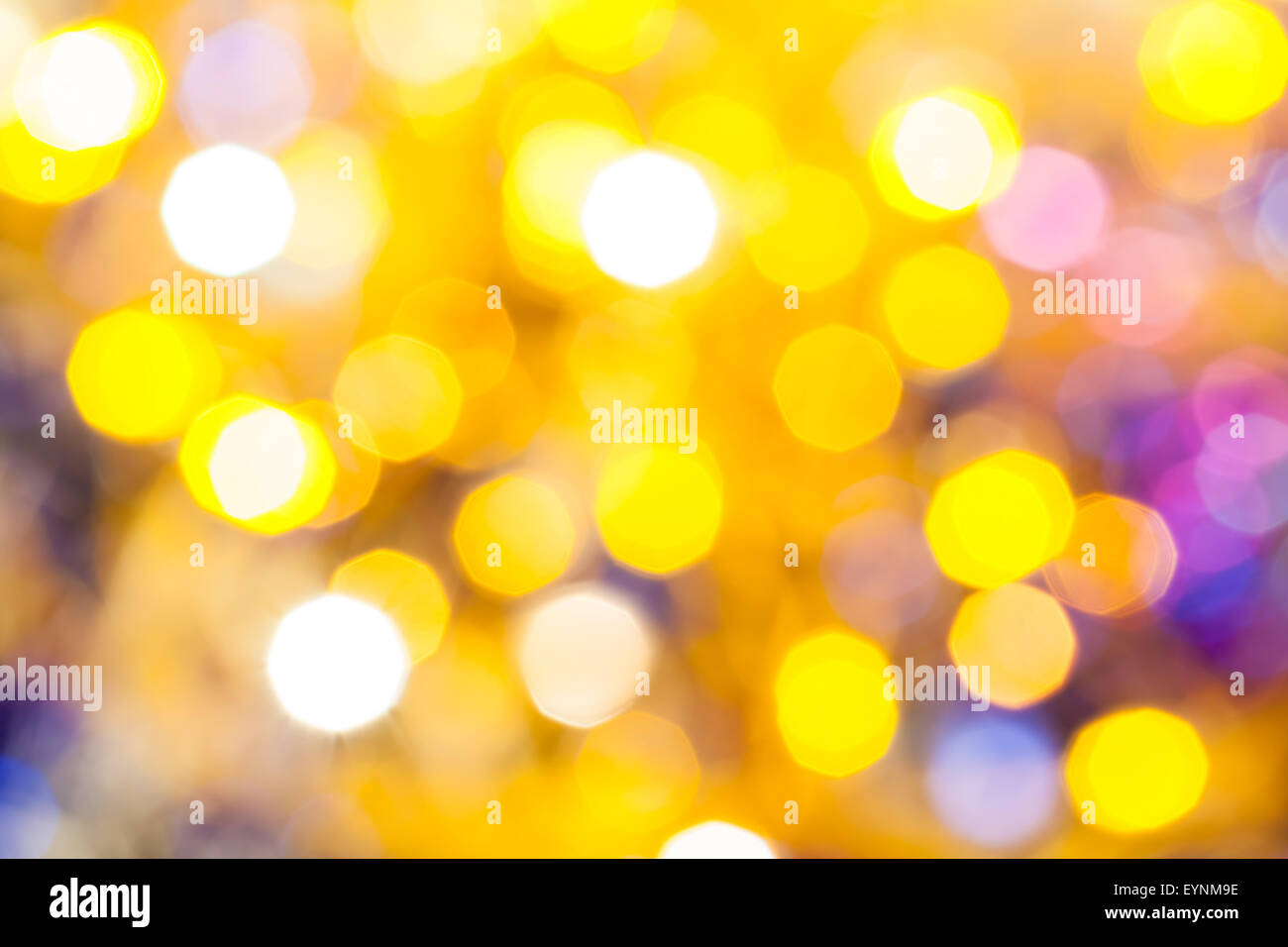 Abstract sfondo sfocato - giallo e viola scintillanti luci di Natale di le ghirlande elettriche su albero di Natale Foto Stock