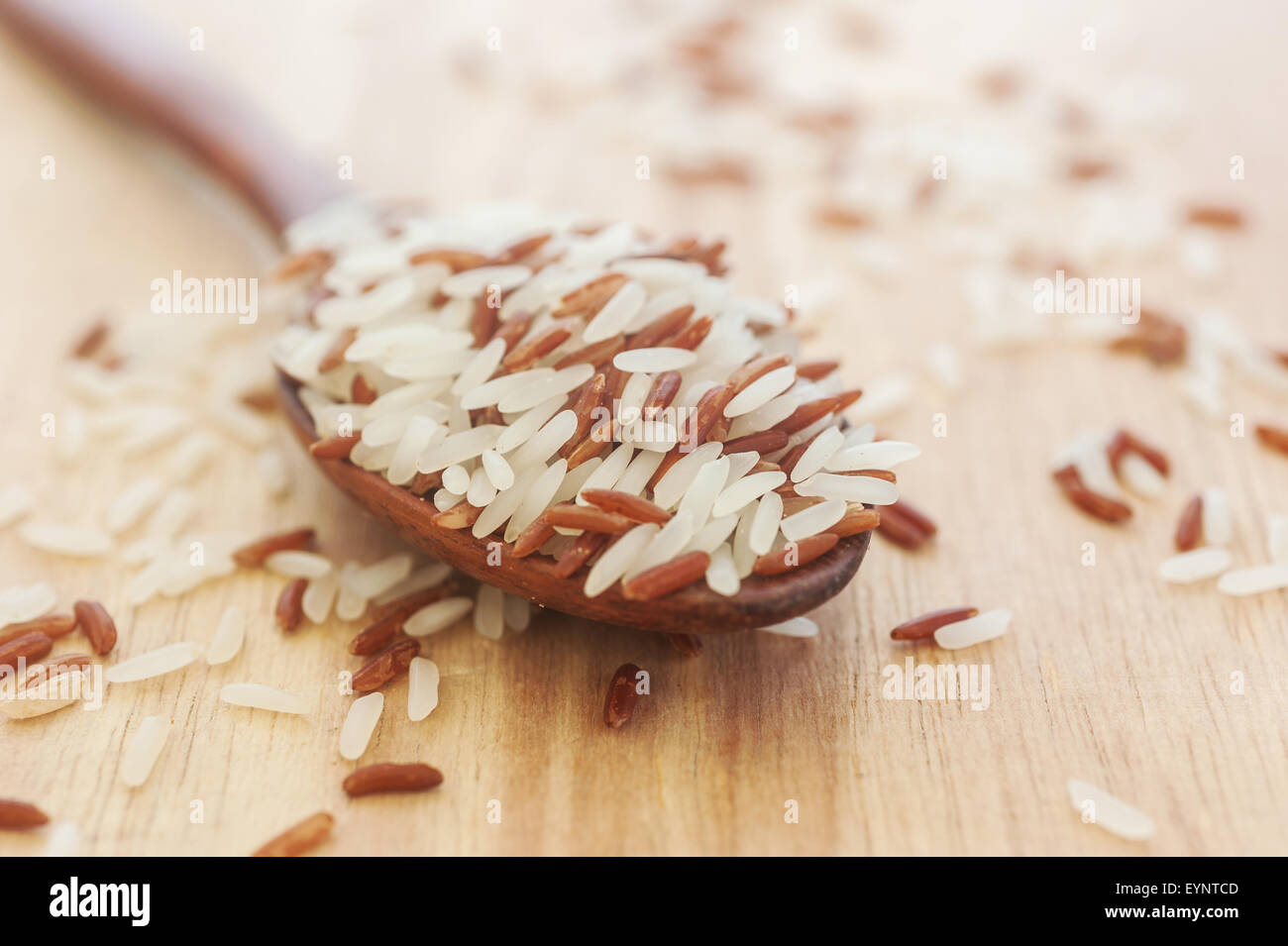 Riso berry, riso marrone in cucchiaio di legno su legno, fuoco selettivo Foto Stock