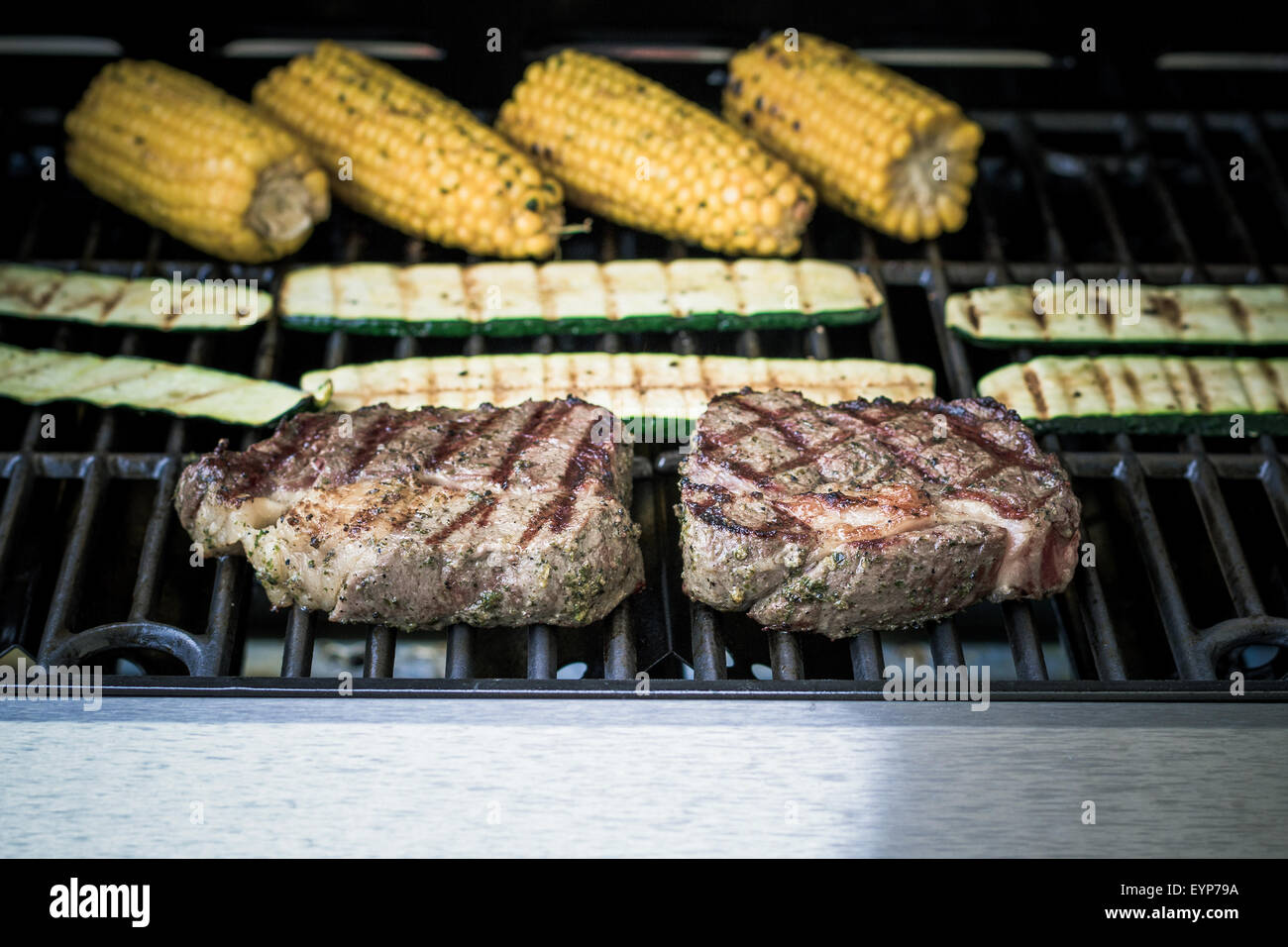 Costata di manzo con zucchine e mais sul grill a gas, soft focus Foto Stock