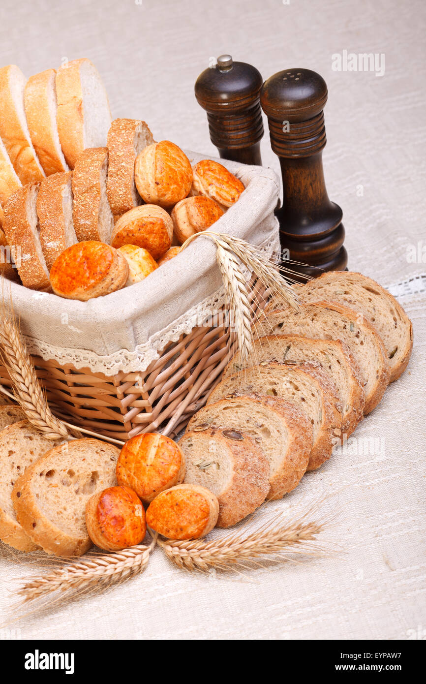 Un assortimento di prodotti da forno tagliata a fette, disposte nel cestello di piccole dimensioni. Spighe di grano di fronte, il sale e il pepe dietro Foto Stock