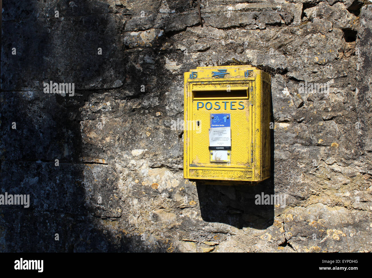 Il francese metallo giallo postal (la Poste) lettera inviare casella sul muro di pietra, pezzata luce solare Foto Stock