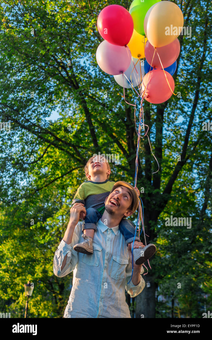 Padre e figlio a piedi nel parco con palloncini in una serata estiva Foto Stock