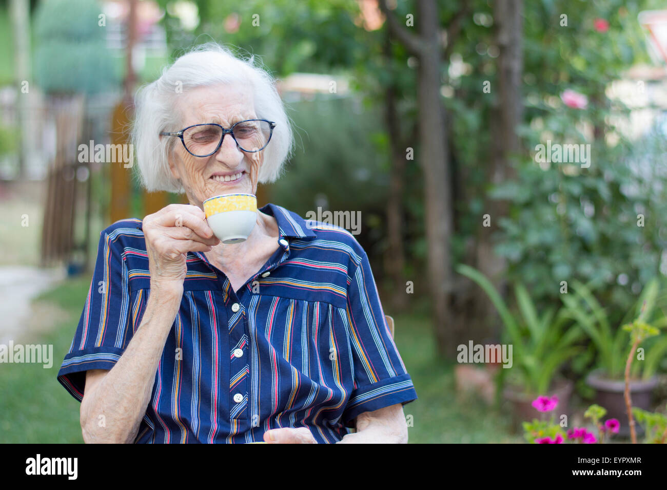 Sorridente vecchia nonna avente tazza di caffè all'aperto Foto Stock