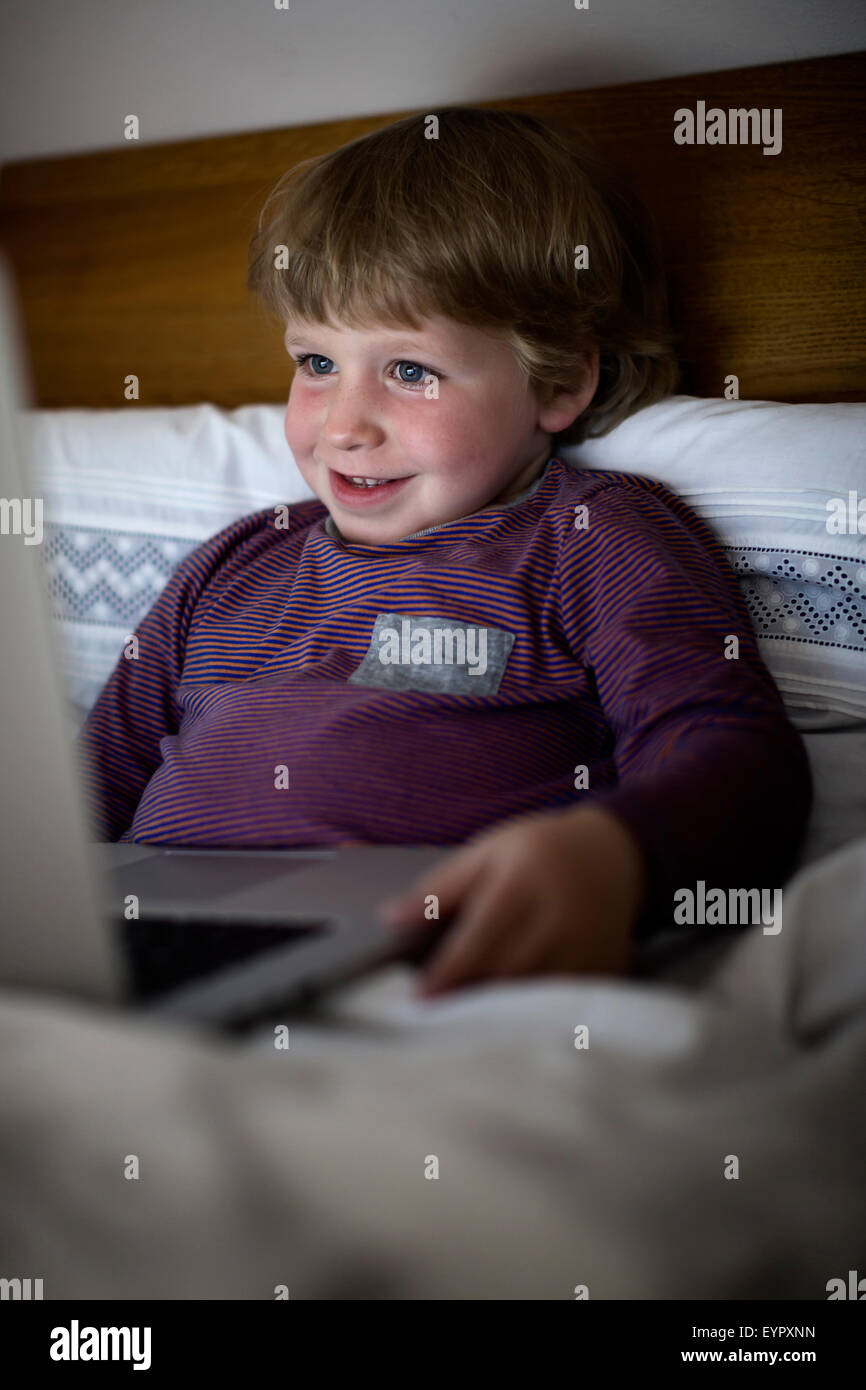 Stanco ragazzo di sera a letto con il notebook. Foto Stock