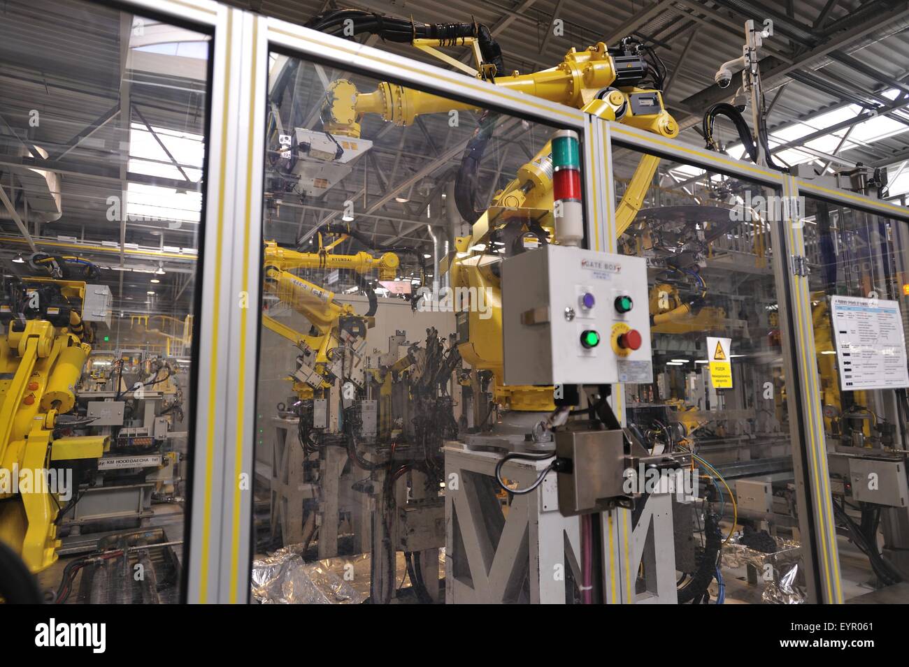 All'interno di una moderna fabbrica di automobili e veicoli e parti si muovono attraverso il processo di produzione, robot dietro lo schermo di sicurezza Foto Stock