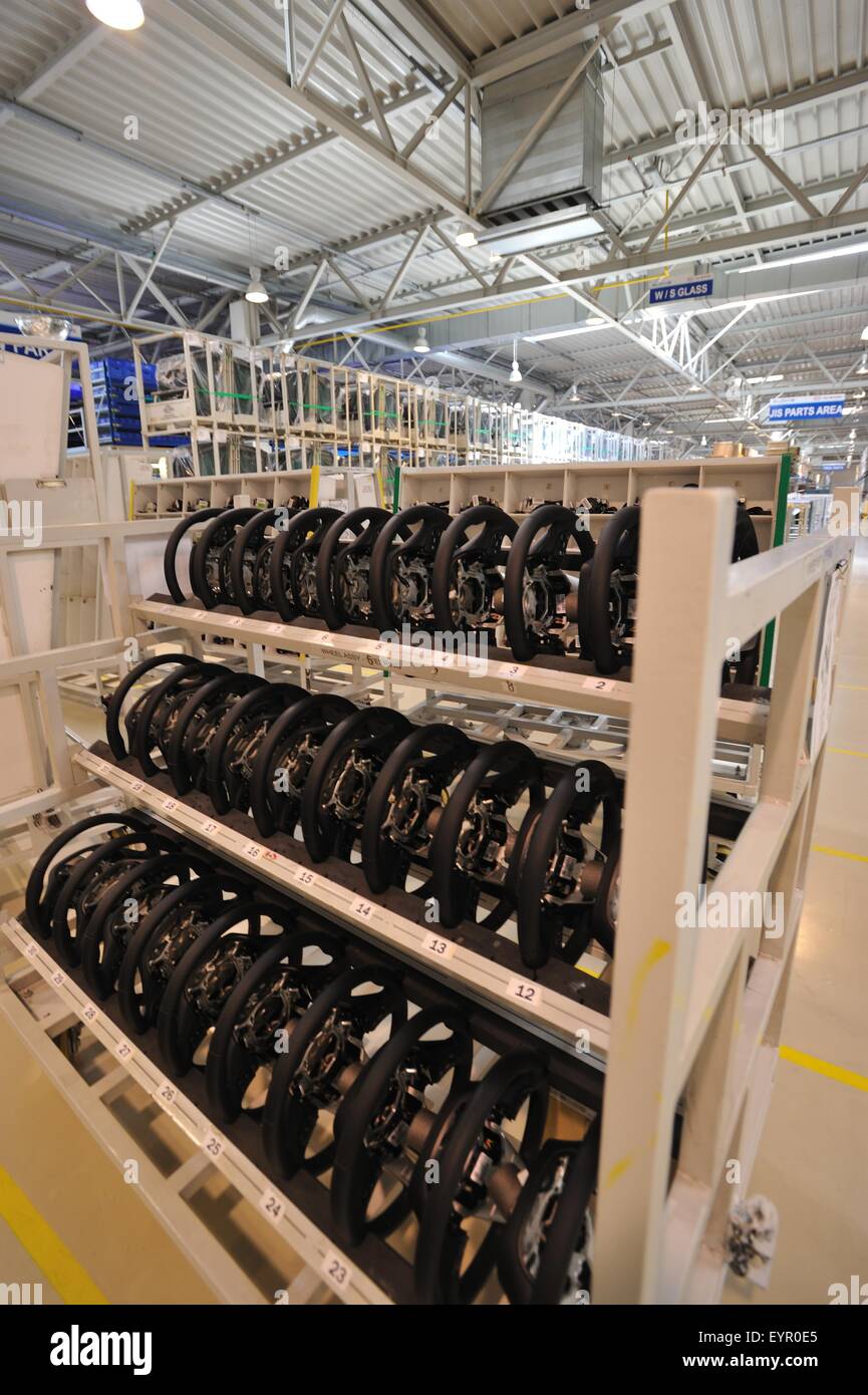 All'interno di una moderna fabbrica di automobili e veicoli e parti si muovono attraverso il processo di produzione, ruote sterzanti in attesa di andare Foto Stock