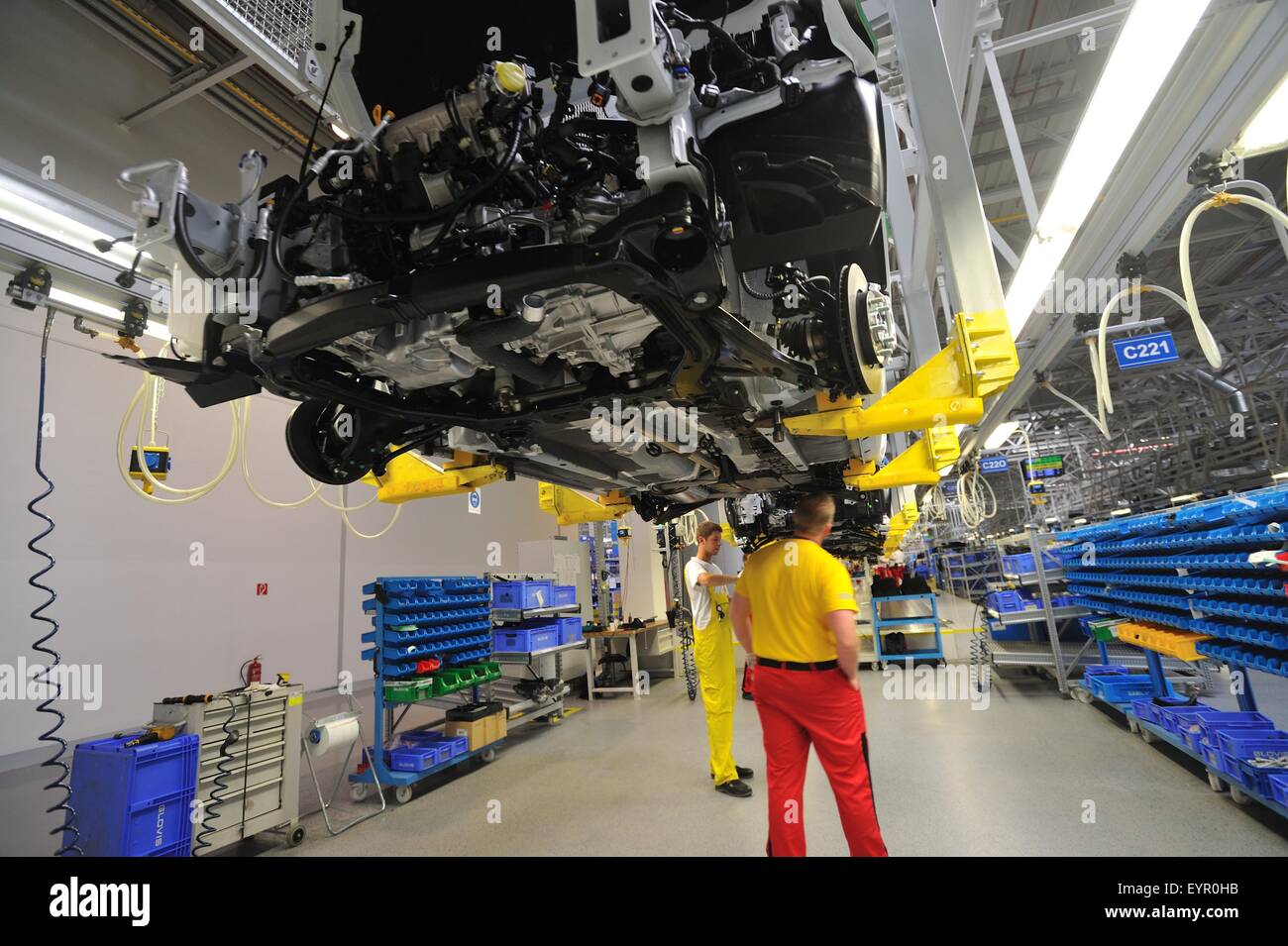 All'interno di una moderna fabbrica di automobili e veicoli e parti si muovono attraverso il processo di produzione, lavorando sotto le automobili sospeso Foto Stock