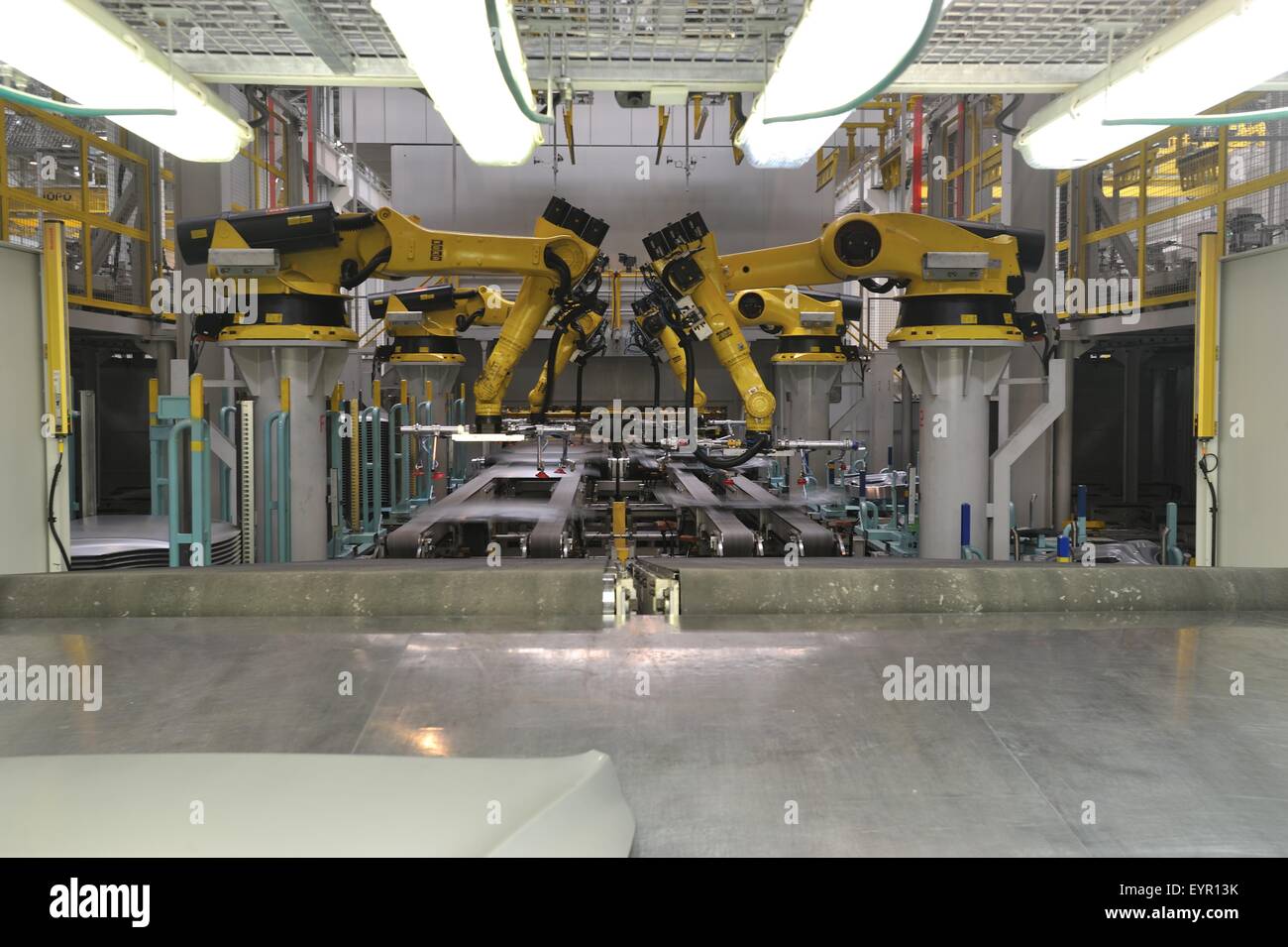 All'interno di una moderna fabbrica di automobili e veicoli e parti si muovono attraverso il processo di produzione, bracci robot pick up pannelli pressati Foto Stock