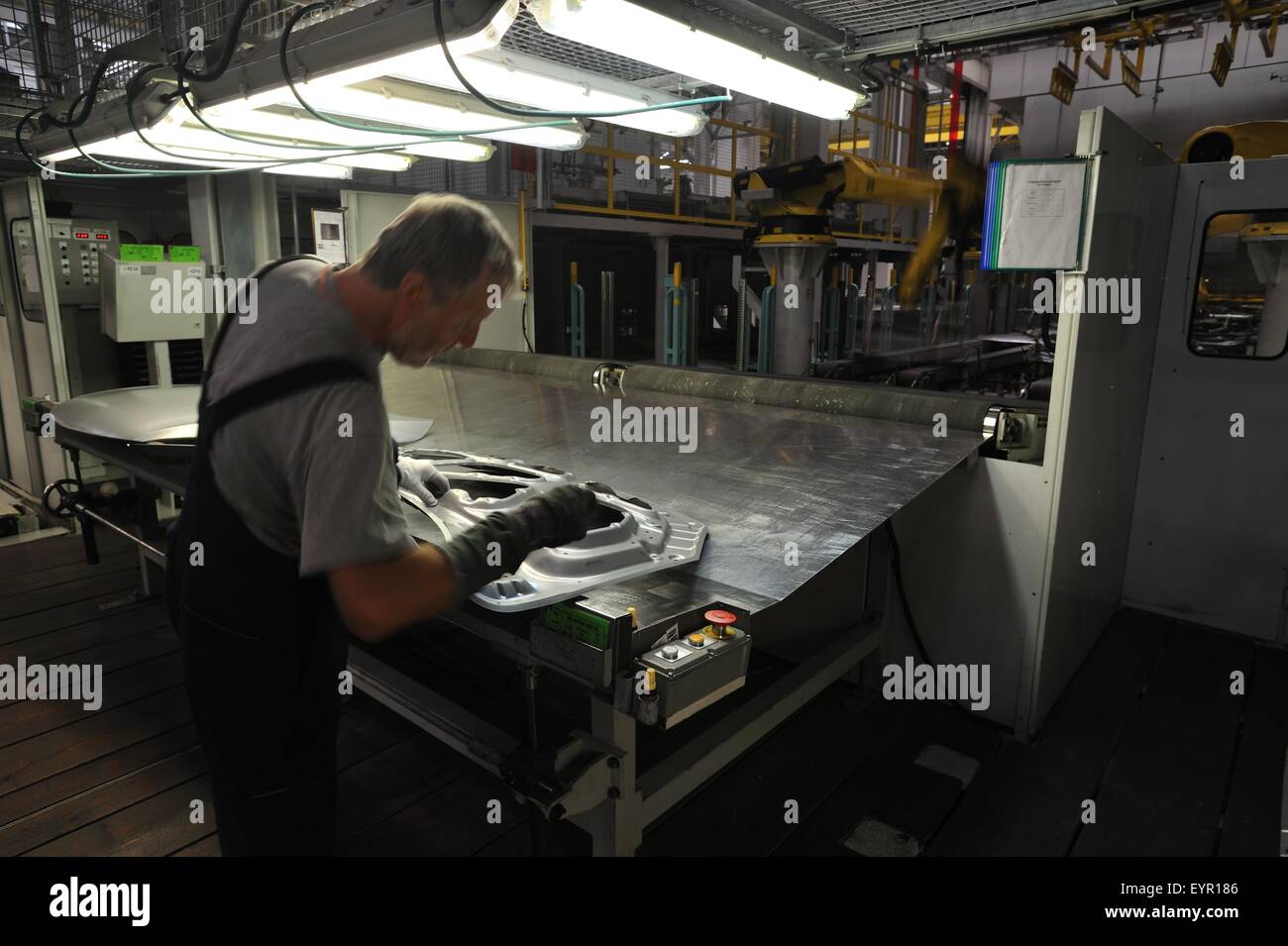 All'interno di una moderna fabbrica di automobili e veicoli e parti si muovono attraverso il processo di produzione, un lavoratore controlla un fresco pannello stampato Foto Stock