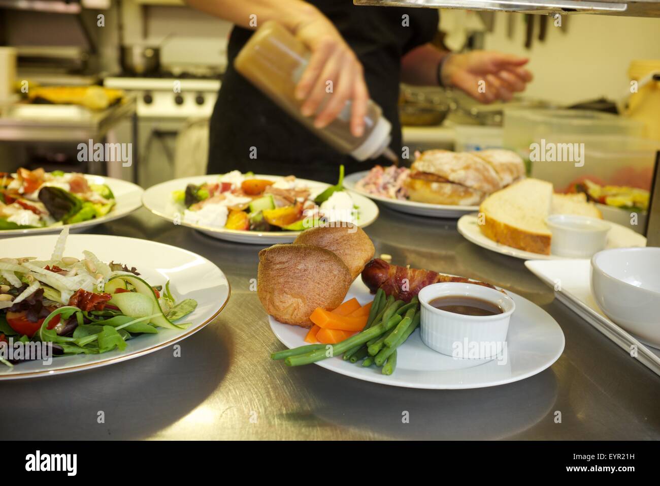 Una femmina di chef le piastre su abiti e insalata in un professionista cafe cucina Foto Stock