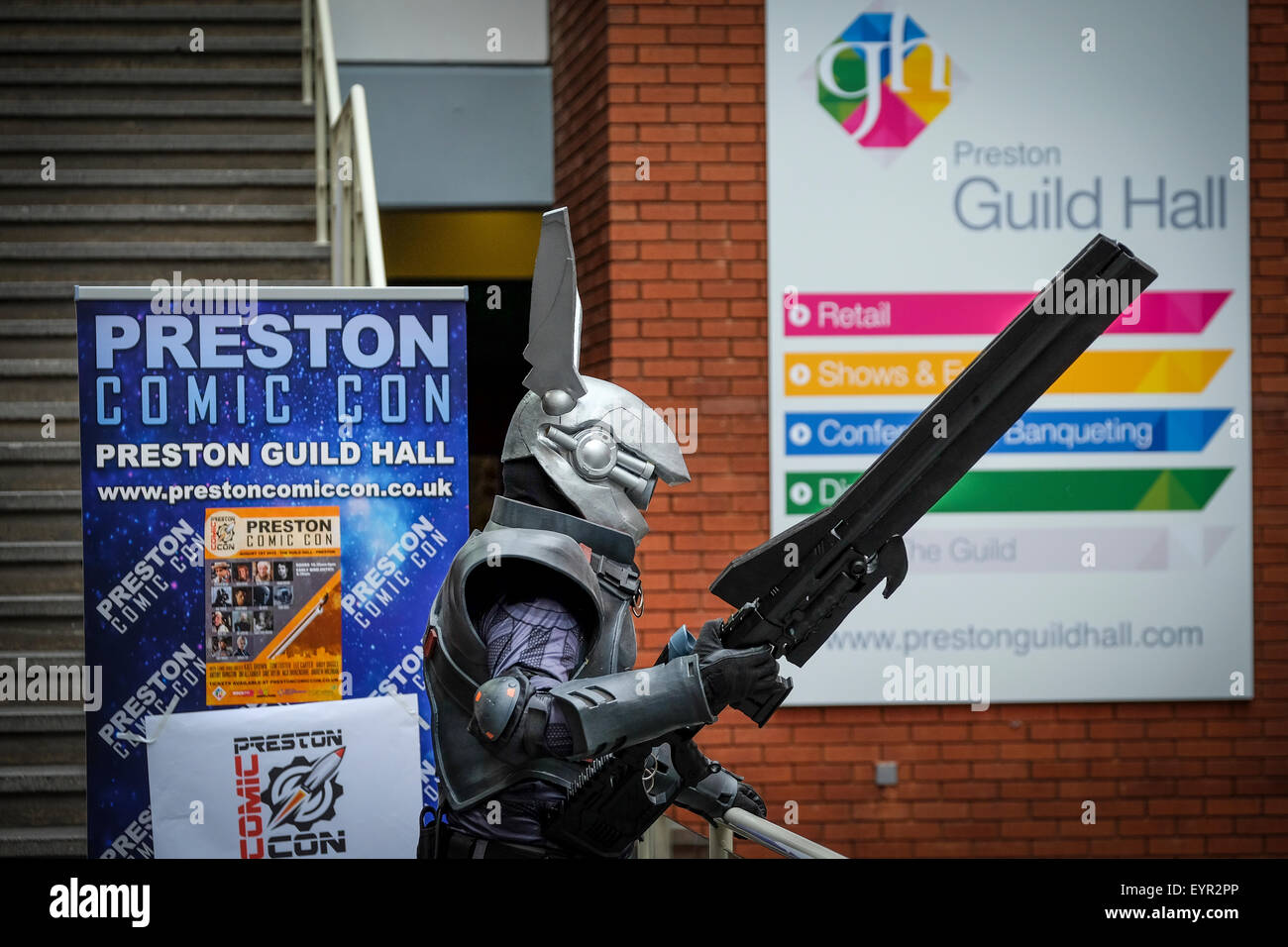 Preston, Regno Unito. Fumetto con evento a Preston Guild Hall con uomo in costume futuristico e pistola di grandi dimensioni accanto al caso banner. Foto Stock