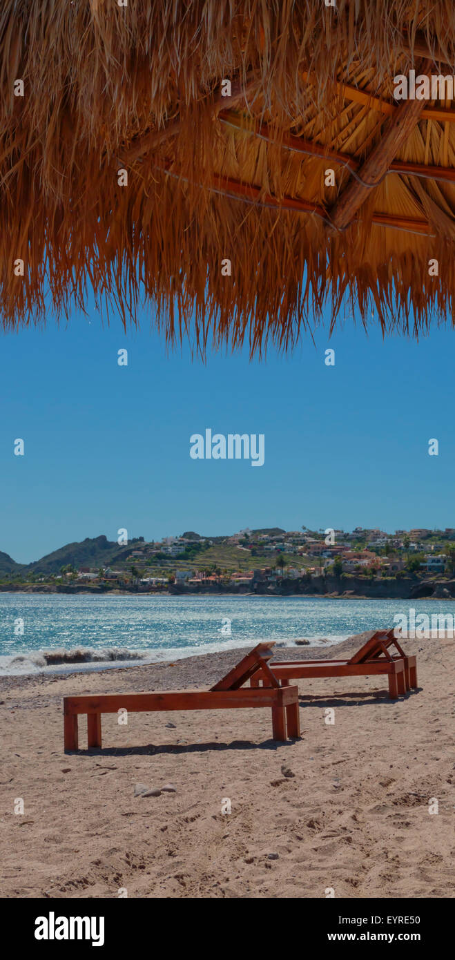 Paglia di paglia tiki hut e sedie a sdraio su di una spiaggia di sabbia Foto Stock