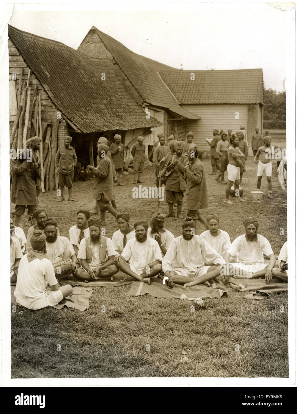 Questa immagine cattura un gruppo di soldati sikh che cantano canti religiosi fuori dai loro billetti a le Sart, in Francia. Riflette le loro pratiche culturali e spirituali durante la prima guerra mondiale, enfatizzando la loro devozione religiosa e il servizio militare. Foto Stock