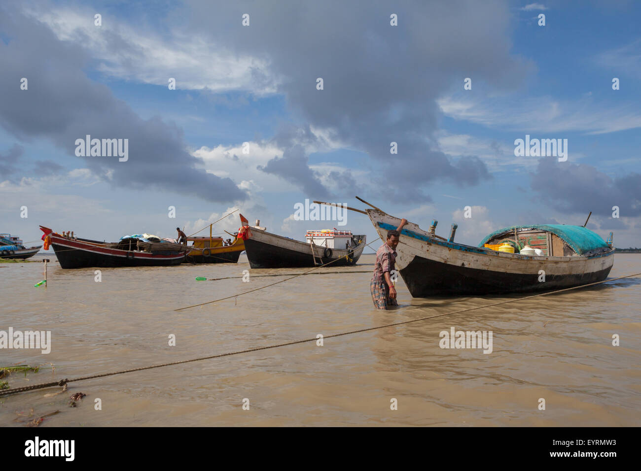 L'uomo cammina verso barche da pesca sul fiume. Foto Stock