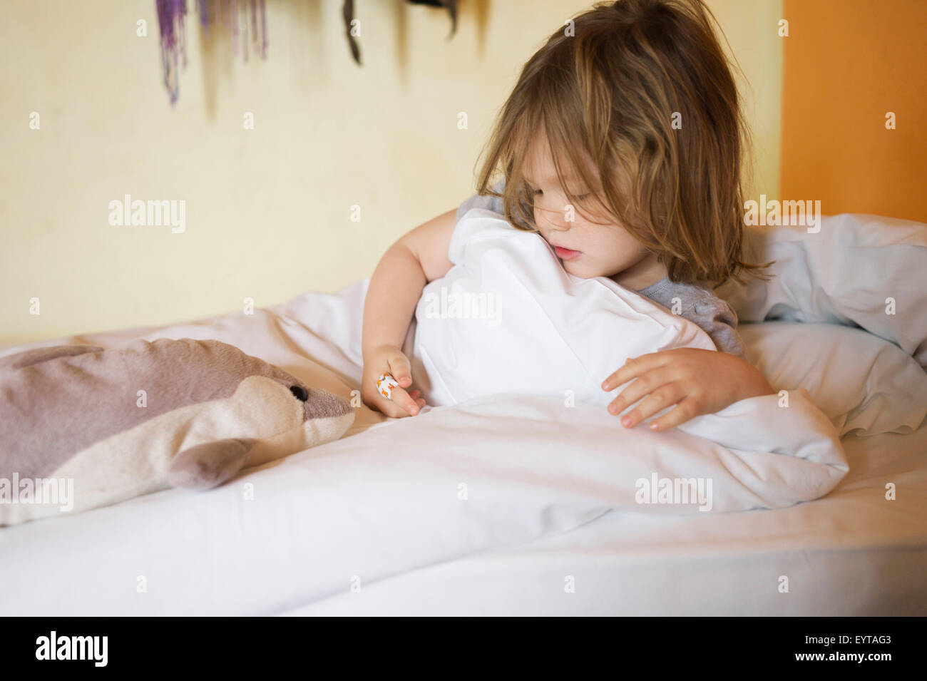 Le ragazze, 3 anni, letto, giacente, eying cerotto sul dito, Foto Stock