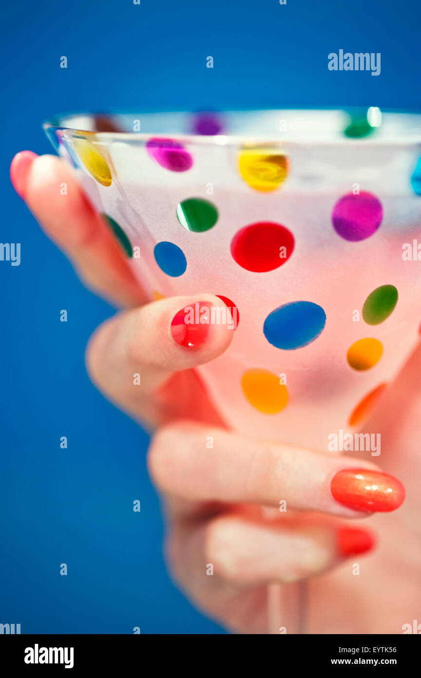 Donna con mano dipinto luminosamente unghie tenendo un coloratissimo e festoso cocktail / coppetta Martini Foto Stock