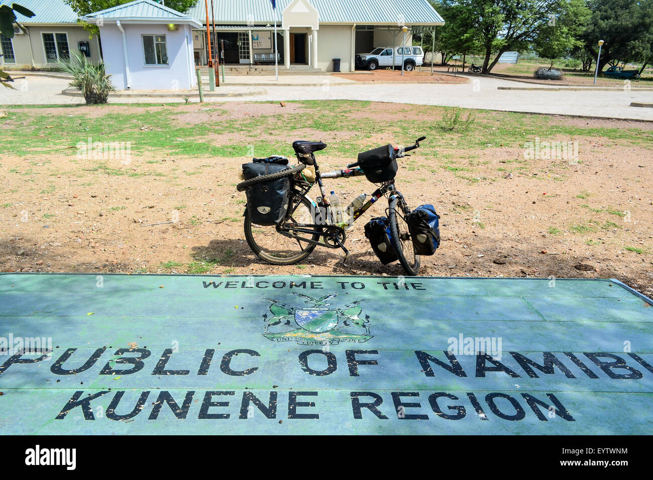 Confine namibiano post segno - la lettura di Repubblica di Namibia - regione di Kunene, al confine con l'Angola, e di una bicicletta da turismo Foto Stock