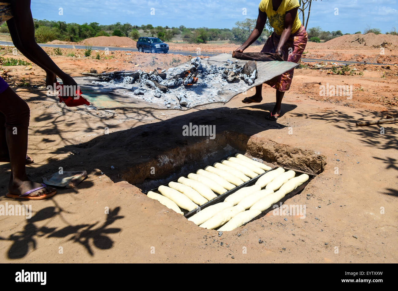 Le donne angolane la cottura del pane nel terreno sotto un incendio Foto Stock