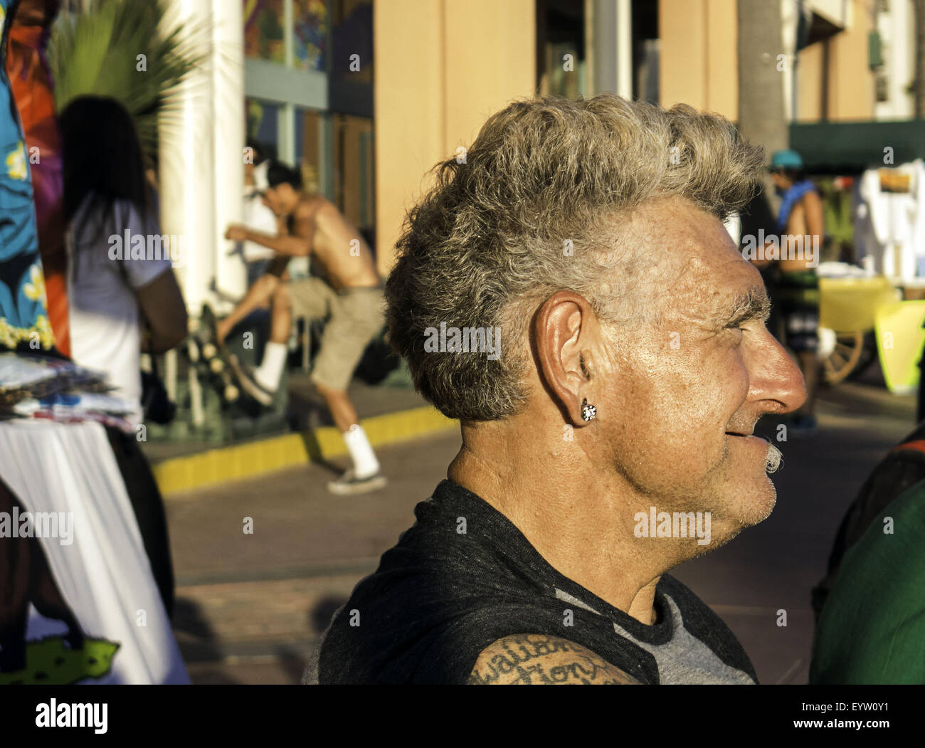 Huntington Beach, CA, Stati Uniti d'America. 1 agosto, 2015. Agosto 1, 2015 - Huntington Beach, California, Stati Uniti - Kawika Hall, 54, da Oahu, Hawaii, orologi la gente passa da seduti su una panchina di fronte al furgoni US Open di surf. La sala era in città per aiutare con il concorso. La copertura della cultura che è attratta verso il 2015 furgoni US Open di surf. Immagine di credito: Sean DuFrene/ZUMAPRESS.com © Sean Dufrene/ZUMA filo/Alamy Live News Foto Stock