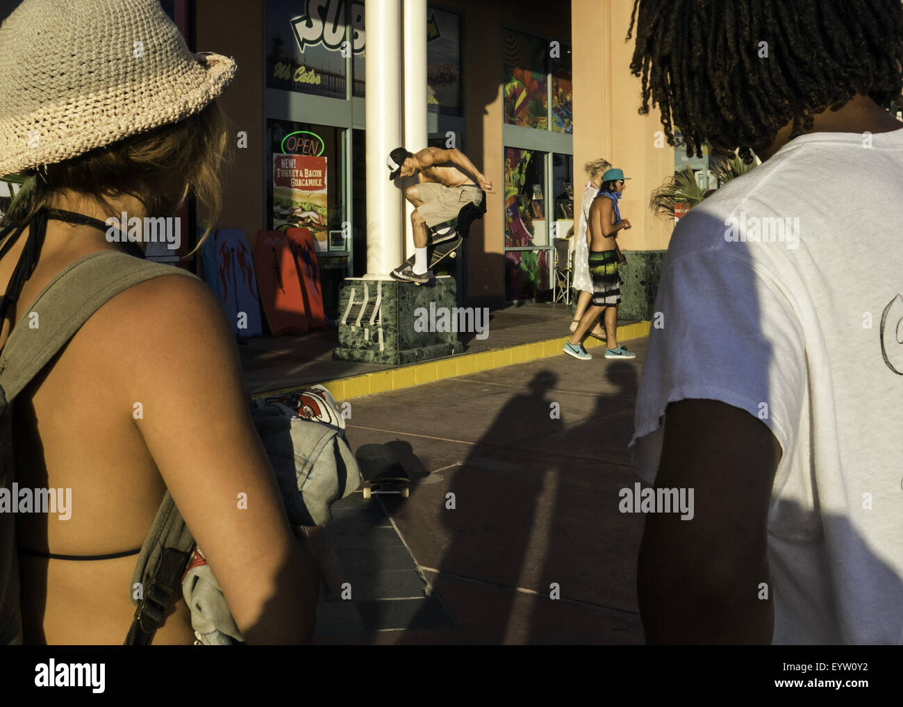 Huntington Beach, CA, Stati Uniti d'America. 1 agosto, 2015. Agosto 1, 2015 - Huntington Beach, California, Stati Uniti - Zola Hauge (sinistra), da Topanga, California, e Khidhar Geban (a destra), 22 da Hermosa Beach, CA, guarda Bryan Torrellas, 23, da Hermosa Beach, smerigliare un cordolo di marciapiede davanti ai negozi vicino alla strada principale e Pacific Coast Highway. Hauge è piaciuto in tutto e per tutto il 2015 furgoni US Open di surf, soprattutto per le persone. Geban goduto la visione di Chris Russell skateboard nei furgoni US Open di surf skateboard contest. La copertura della cultura che è attratta verso il 2015 furgoni US Open di surf. Im di credito Foto Stock