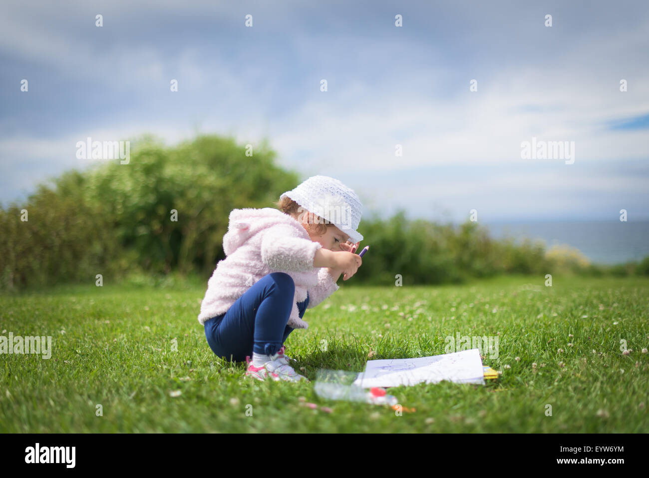 Poco ragazza seduta sull'erba Foto Stock