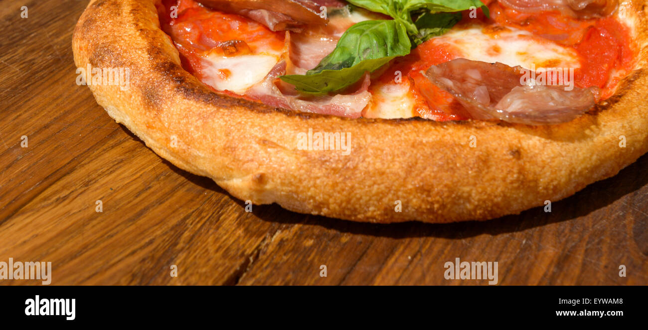 Pizza Fresca su una spessa la pasta su un vassoio in legno Foto Stock