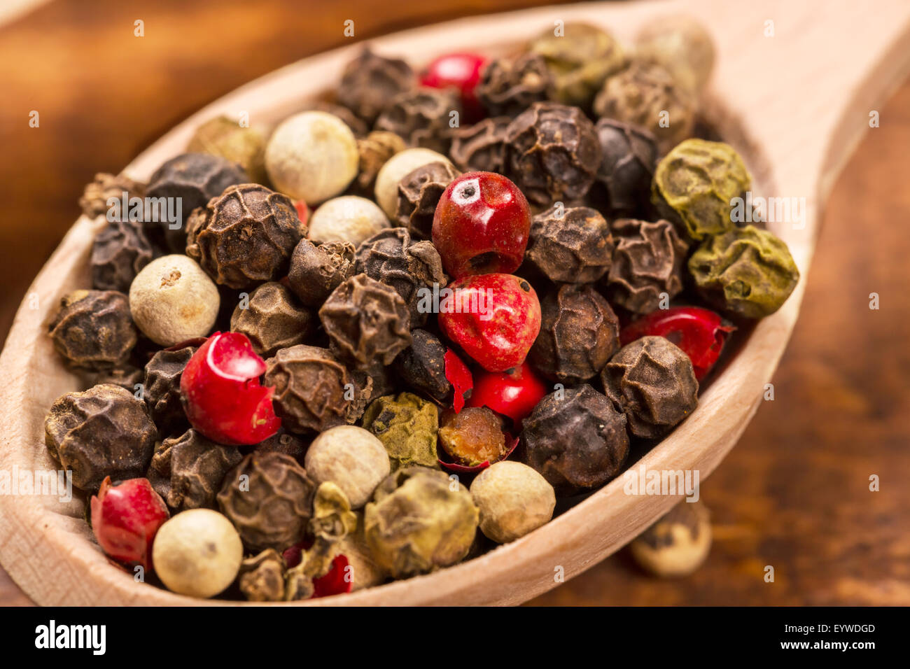 Semi di pepe in cucchiaio di legno sul tavolo di legno Foto Stock