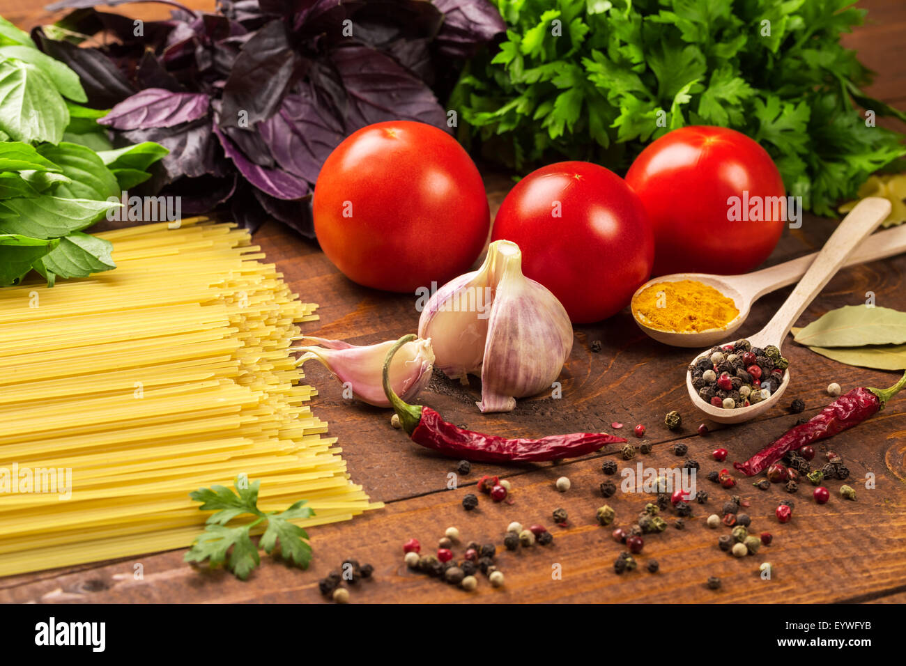 Materie pasta, verdure, basilico e spezie sulla tavola di legno Foto Stock